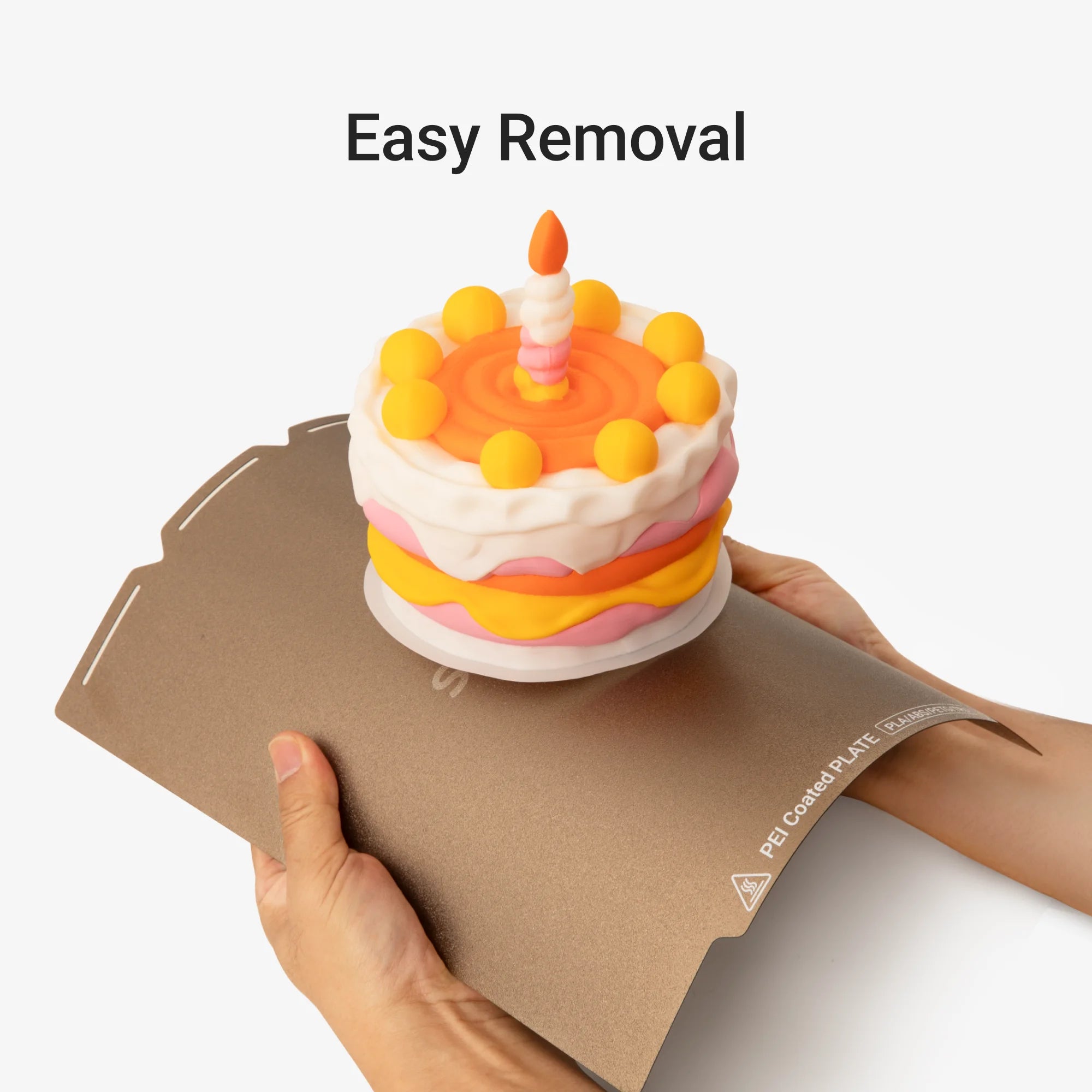 Textured PEI Steel Plate flexing to release a colorful printed cake model, showing easy removal.
